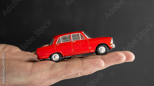 Red Little model car on the palm. buy or insurance car concept.