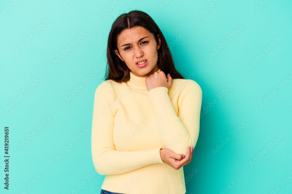 Obraz premium Young Indian woman isolated on blue background massaging elbow, suffering after a bad movement.