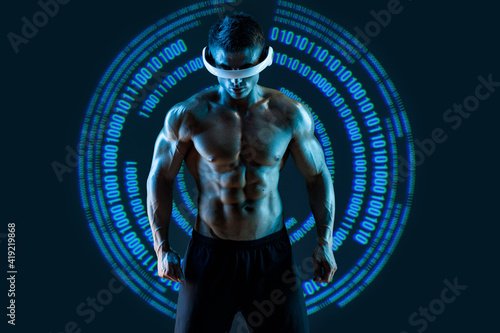 Muscular model sports young man in glasses of virtual reality on dark background. Blue neon light. Futuristic holographic interface to display data. Augmented reality, future technology, game concept.