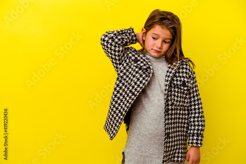 Little caucasian girl isolated on yellow background touching back of head, thinking and making a choice. © Asier