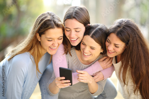 Four happy women checking smart phone content