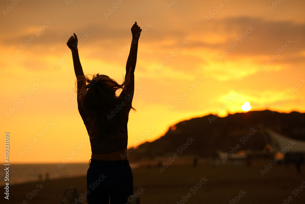 Woman silhouette raising arms celebrating at sunset