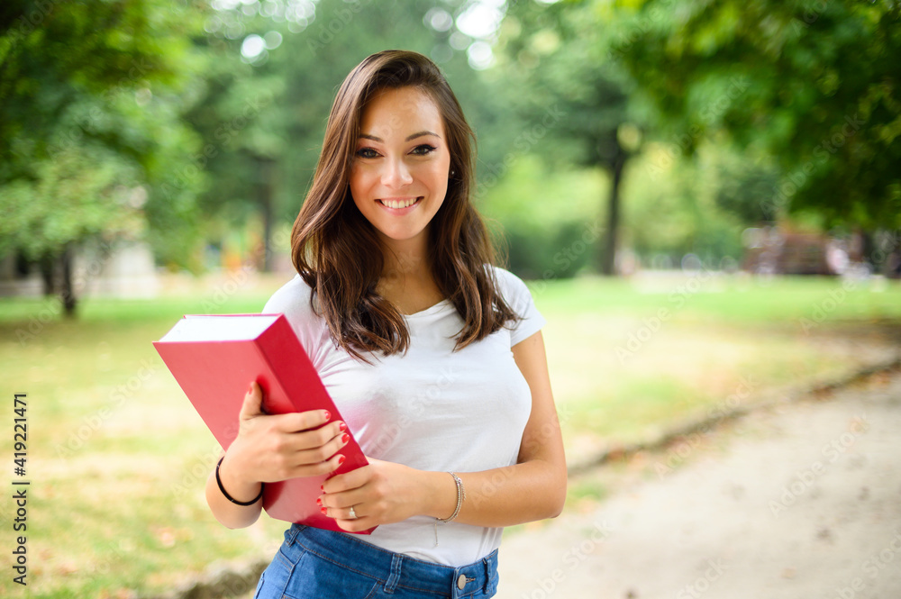 Beautiful female student holding a book outdoor Beautiful female student holding a book outdoor