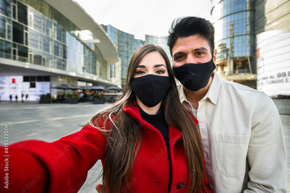 Young couple taking a selfie portrait together outdoor and wearing masks to prevent coronavirus covid 19 pandemic Young couple taking a selfie portrait together outdoor and wearing masks to prevent coronavirus covid 19 pandemic