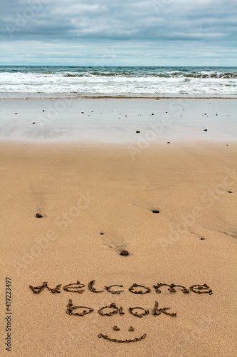 Welcome back words written by hand on the sand of the beach. Holiday traveling vacation reopening concept.