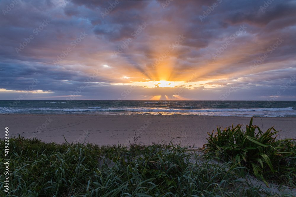 Sunrise on Palm Beach Island in South Florida with storm clouds and sun flares or sunbeams Sunrise on Palm Beach Island in South Florida with storm clouds and sun flares or sunbeams