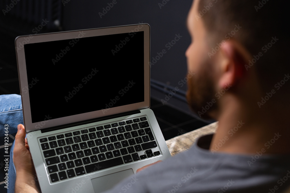 Cropped back photo of young male programmer working at home using laptop. Work from home. Telework. Cropped back photo of young male programmer working at home using laptop. Work from home. Telework.