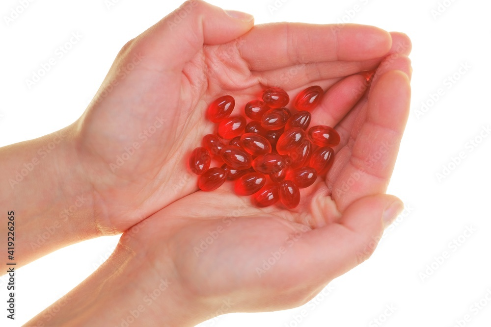 Krill oil capsules. Red gelatin capsules with krill oil in hand
