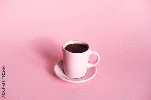 Pink cup of coffee with pink background and coffee beans