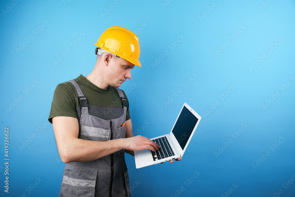 builder holding laptop on blue background with copy space builder holding laptop on blue background with copy space