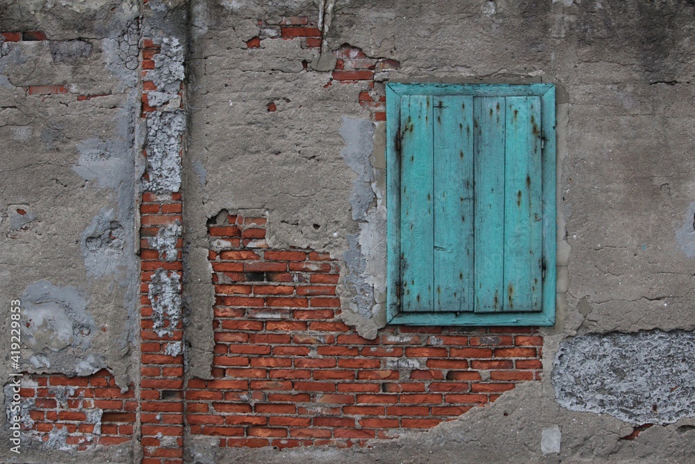 Teal color window on a ruined brick wall.