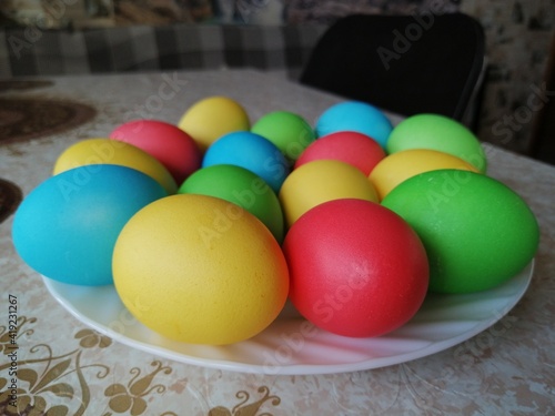 Colorful and bright Easter eggs on a plate on the table at home