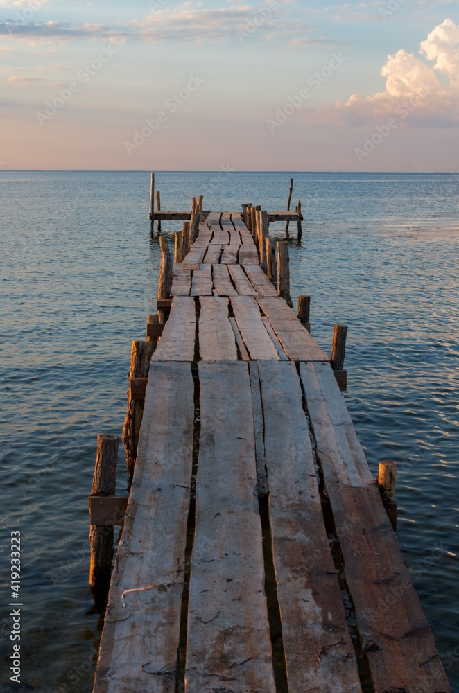 Wooden empty pier by the calm sea at sunset