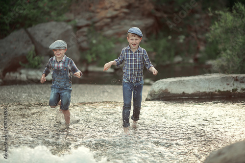 two boys in jeans and shirt playing in the lake on a warm summer day at sunset