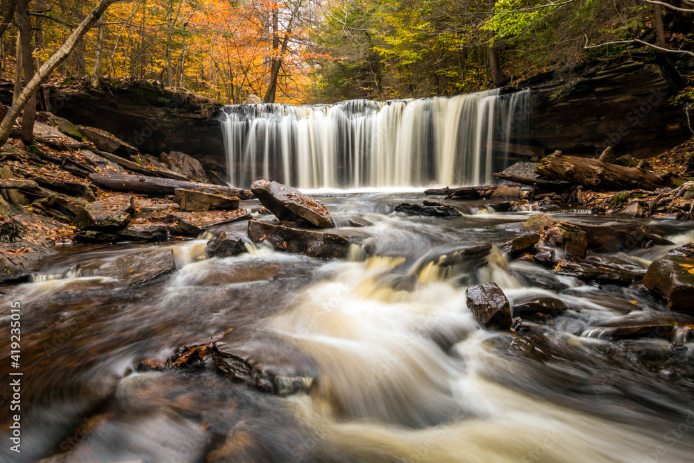 Obraz premium colorful autumn foliage with calming cascading waterfall in Pennsylvania.
