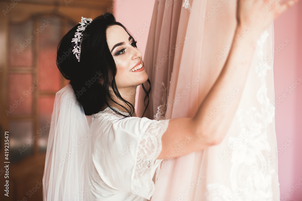 Fototapeta premium Gorgeous bride in robe posing and preparing for the wedding ceremony face in a room