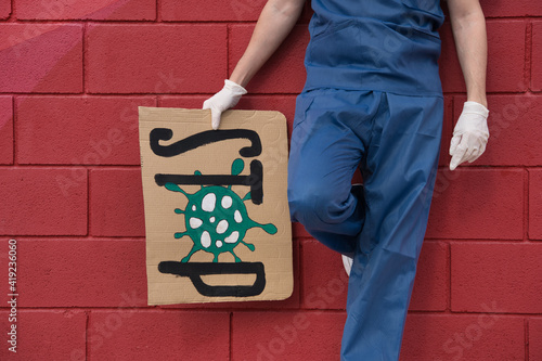 Wallpaper Mural Faceless medic worker wearing uniform and latex gloves holding a cardboard with covid19 message. Torontodigital.ca