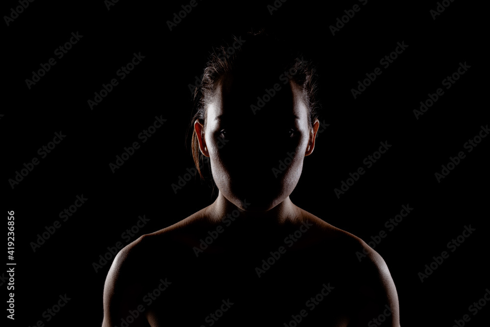 Fototapeta premium silhouette portrait of a beautiful young woman against dark backgroung.