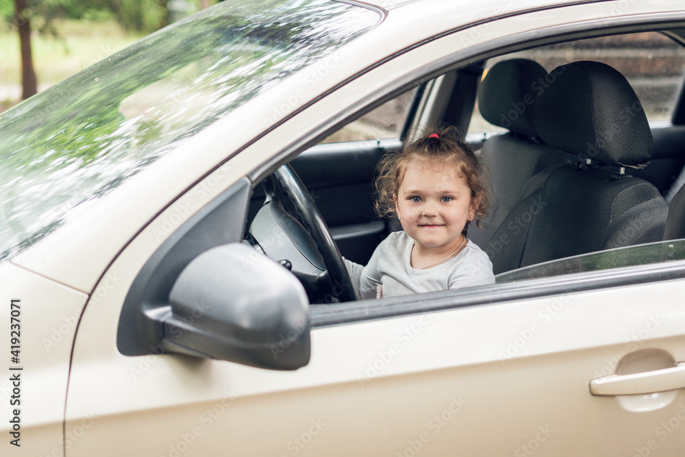 Beautiful cute little girl driving a car