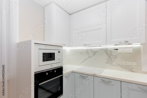 Beautiful white kitchen with grey doors, countertop and appliances.