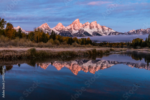 reflection of the alpen glow of the Grand Teton mountains on the Snake River during autumn. © Nathaniel Gonzales