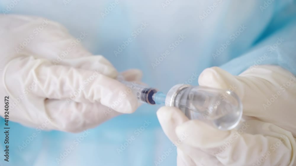 Syringe and Vaccine Vial in the Doctor's Hands. Close-up of Hands in Medical Gloves Filling a Syringe with Medication Syringe and Vaccine Vial in the Doctor's Hands. Close-up of Hands in Medical Gloves Filling a Syringe with Medication