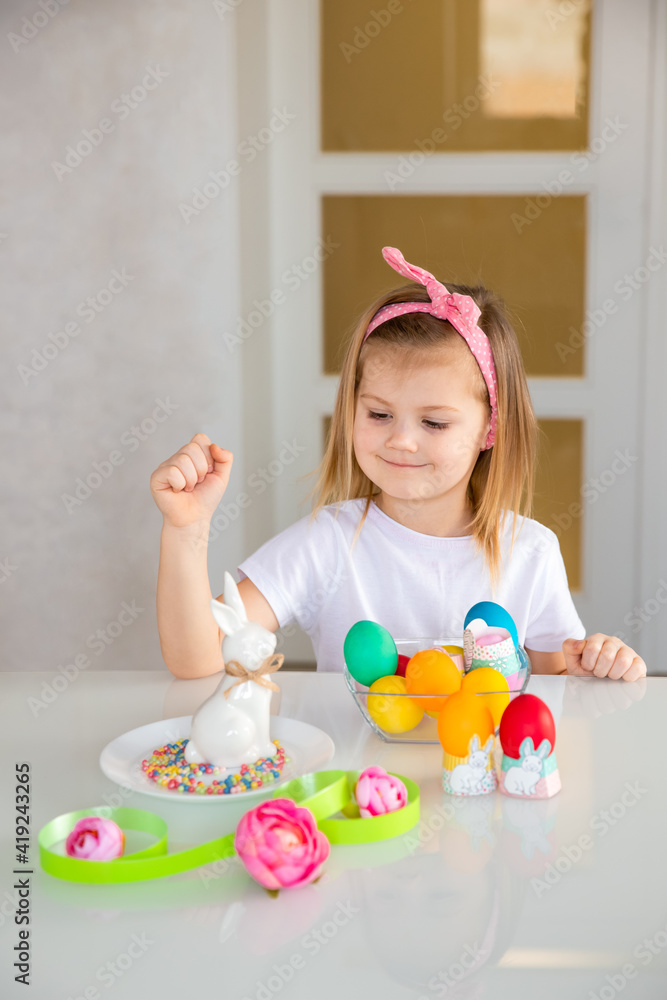 Little girl sitting at the table and decorating Easter eggs Little girl sitting at the table and decorating Easter eggs