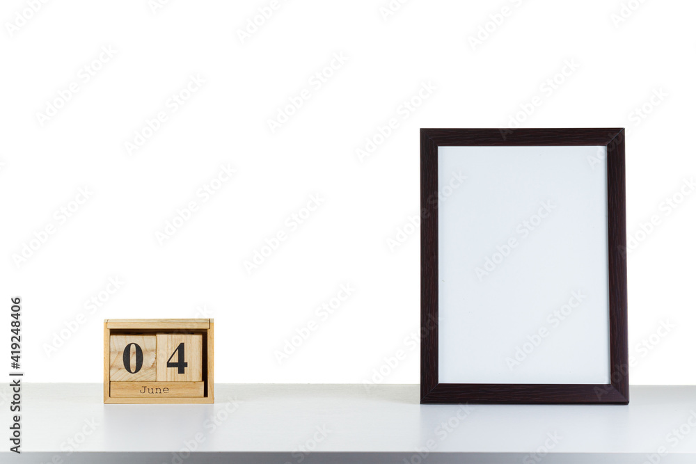 Wooden calendar 04 June with frame for photo on white table and background Wooden calendar 04 June with frame for photo on white table and background