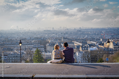 Paris, France - 02 26 2021: Montmartre district. View of Paris from square Louise Michel and a young couple sitting on the steps photo