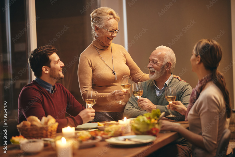 Happy senior woman toasting with her family during a meal at dining table. Happy senior woman toasting with her family during a meal at dining table.