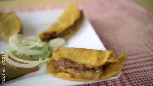 Mexican basket tacos and onion slices on white plate