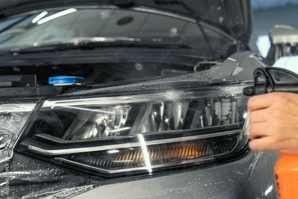 Obraz premium PPF installation on car headlight. Paint Protection Film is protective polyurethane coating for paintwork on car.