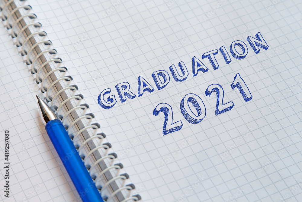 Text GRADUATION 2021 handwritten on sheet of notebook. Graduation day Text GRADUATION 2021 handwritten on sheet of notebook. Graduation day