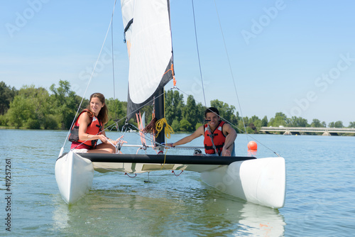 young couple holding ropes on catamaran