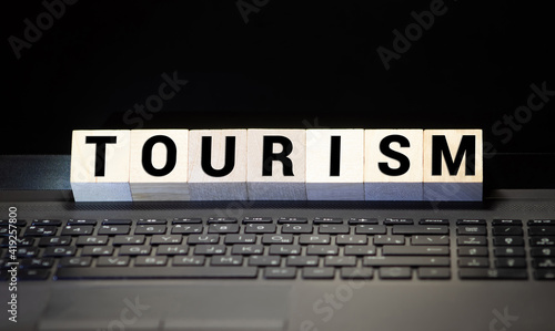 Closeup of word on wooden cube on wooden desk background concept - tourism