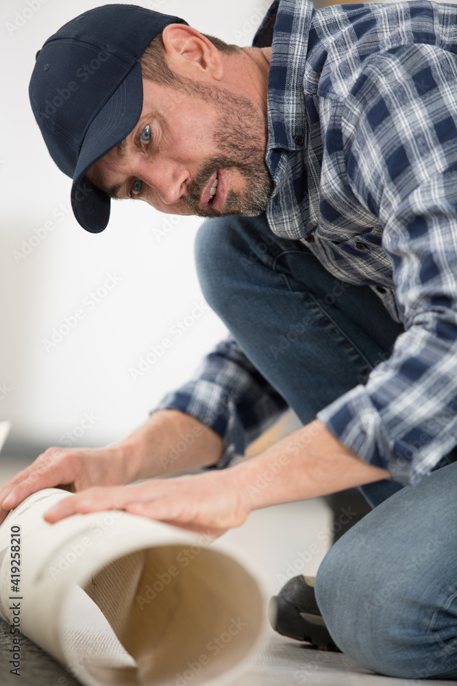male worker unrolling carpet on floor at home male worker unrolling carpet on floor at home