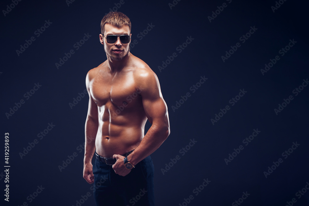 A portrait of a hot guy man without a shirt against dark background with copyspace A portrait of a hot guy man without a shirt against dark background with copyspace
