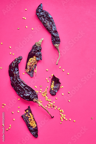 Dried pasilla chile peppers on pink background. photo