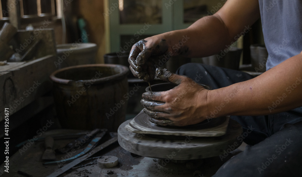 Asian professional artisan potter making art pot or vase handicraft on wheel
