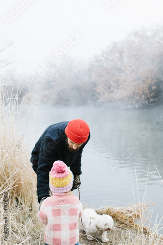 Fotografija Little girl with her father and their dog walking on a greenbelt path next to a