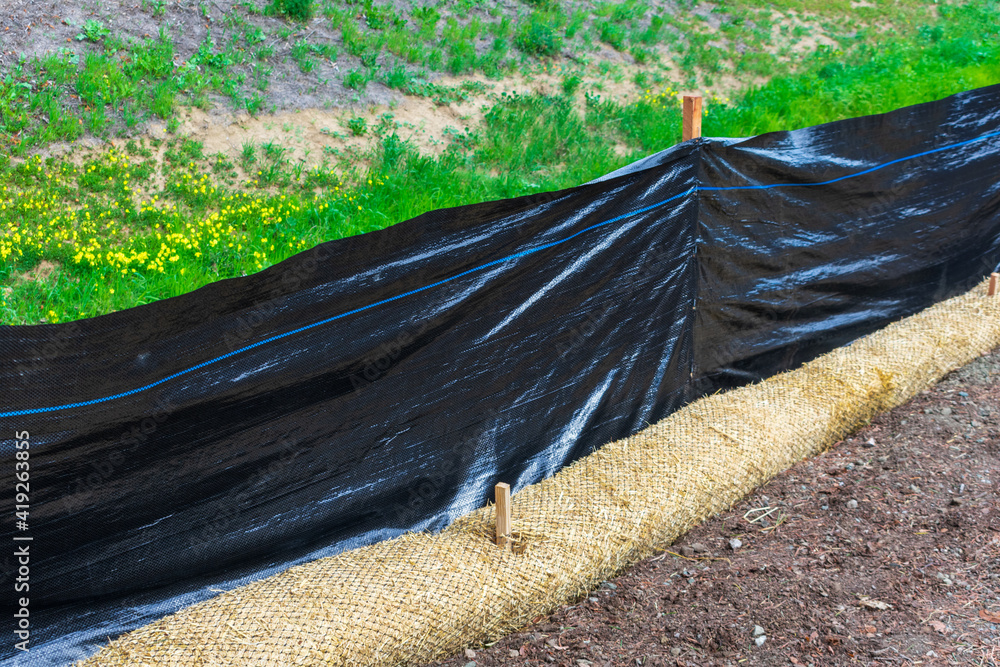 Straw wattles and plastic fence placed along dry waterway to reduce