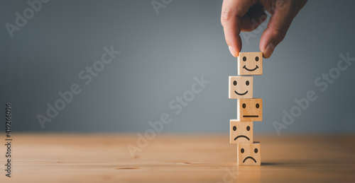 Customer service and Satisfaction concept ,Business people show a feedback with smile face wood cube happy Smiley face icon to give satisfaction in service. rating very impressed. photo