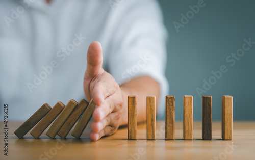 Fotografie Hand Stopping the domino business crisis effect or risk protection concept, busi
