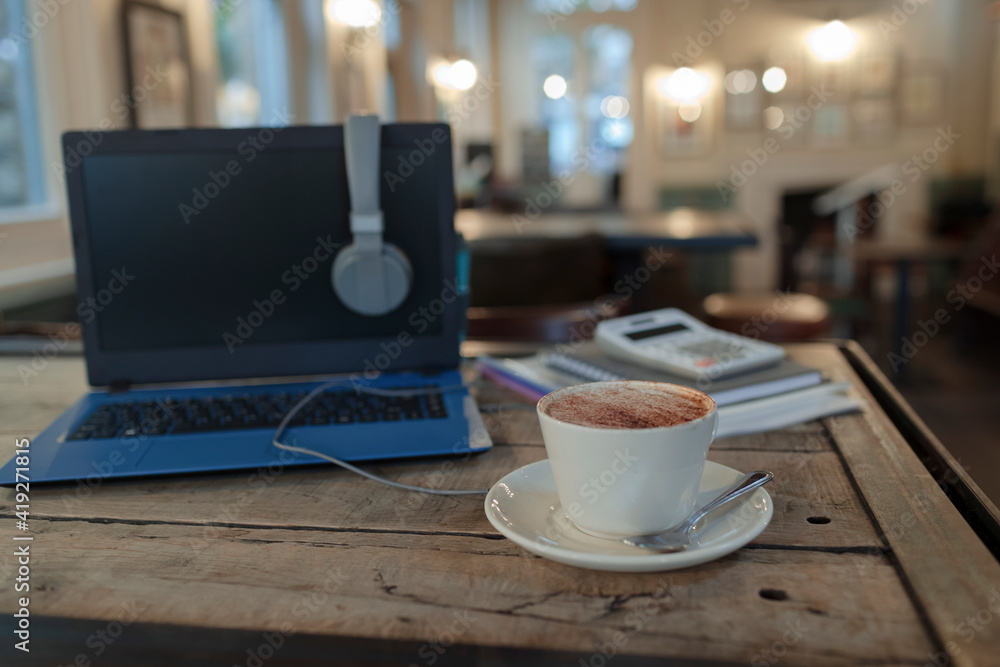 Cappuccino on table next to laptop in cafe Cappuccino on table next to laptop in cafe