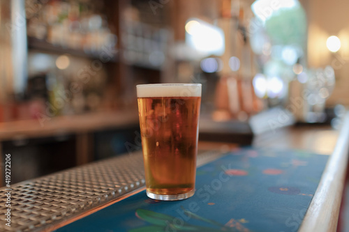 Close up pint of golden beer on pub counter photo