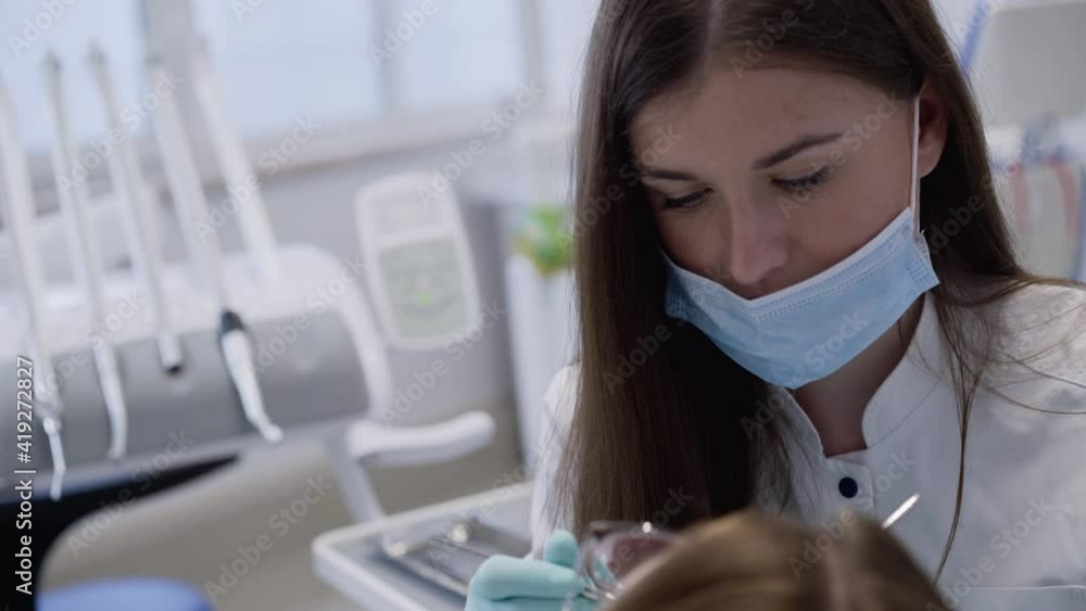 Female dentist in gloves consulting and using tools for working with patient Female dentist in gloves consulting and using tools for working with patient