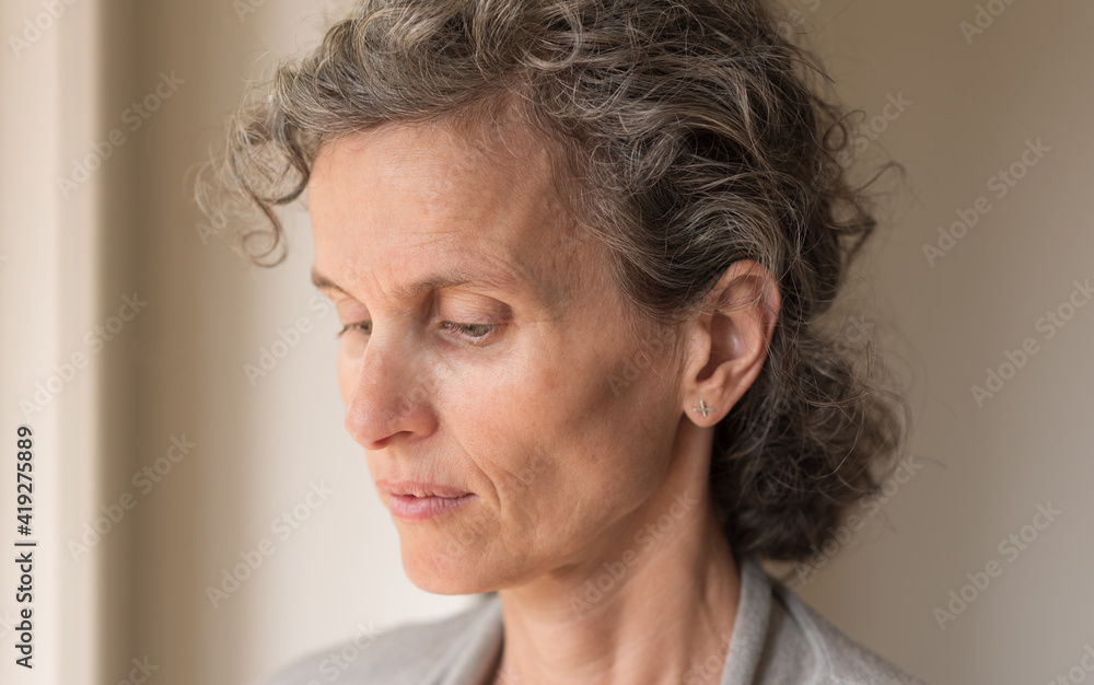 Close up side view of middle aged woman with grey hair looking down (selective focus) Close up side view of middle aged woman with grey hair looking down (selective focus)