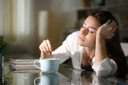 Fotografija Sleepy woman stirring coffee in the morning
