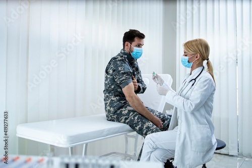 Vaccination of the military against corona virus. Soldier in uniform getting vaccine shot during pandemic.