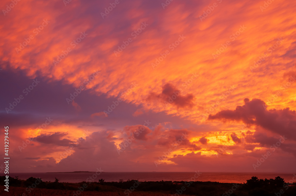 An impressive sunrise with the sky full of colorful clouds in nice formation and painting the ocean with red color. Iriomote Island.